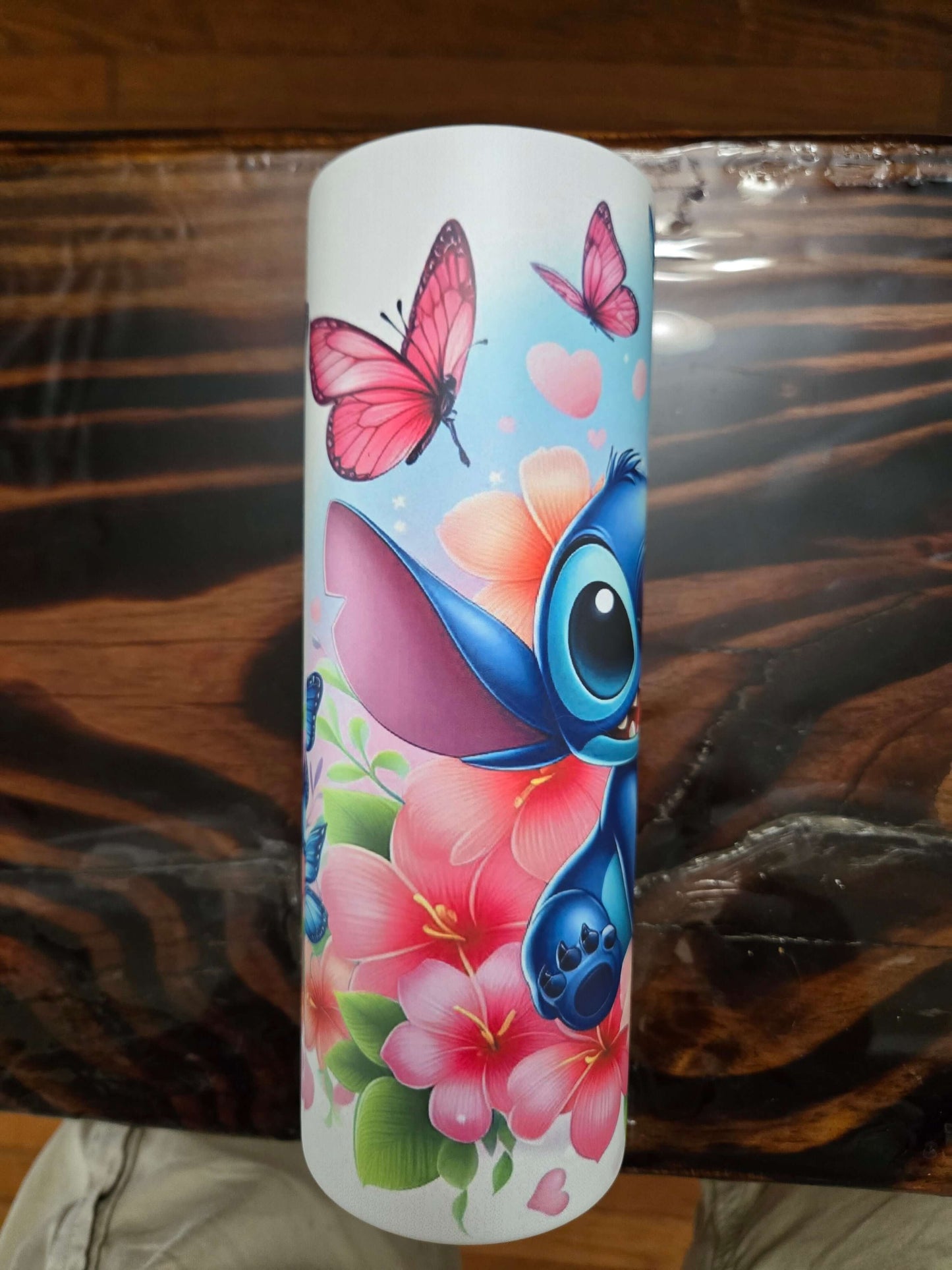 Vibrant design of Stitch with butterflies and pink flowers on a 20oz tumbler cup.