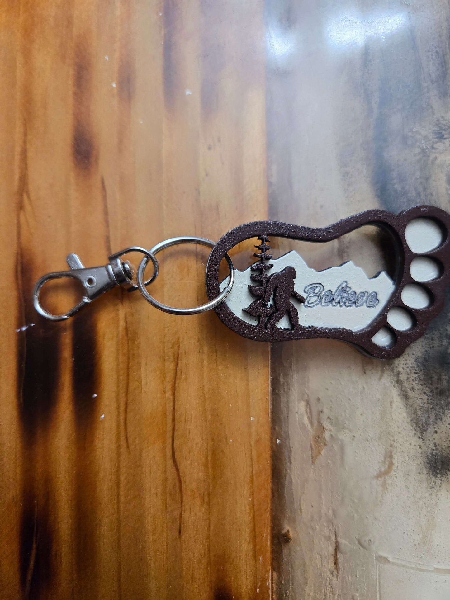 Bigfoot keychain accessory featuring a carved design and 'Believer' text, perfect for organizing on the go.