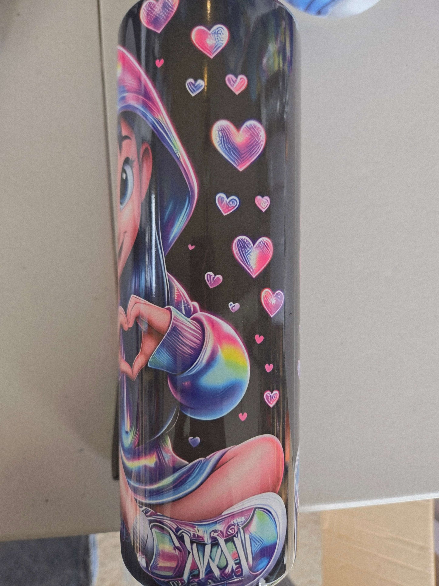 Colorful tumbler featuring a cartoon character making a heart shape with colorful hearts around, perfect for home or travel use.