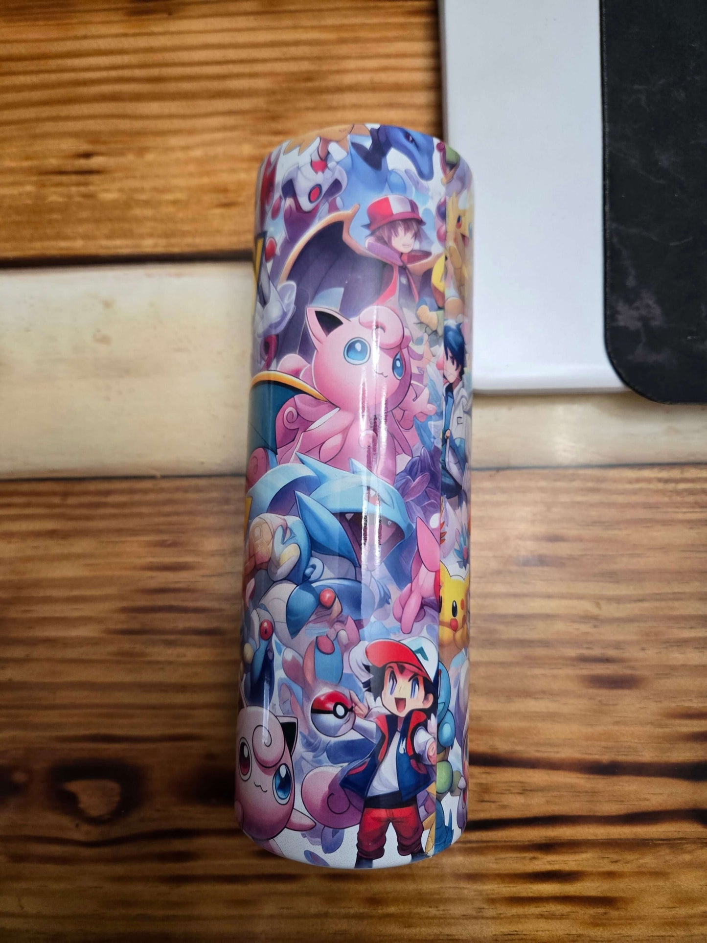 Vibrant Pokémon tumbler cup featuring iconic Pokémon characters and a trainer, perfect for hydration on the go.