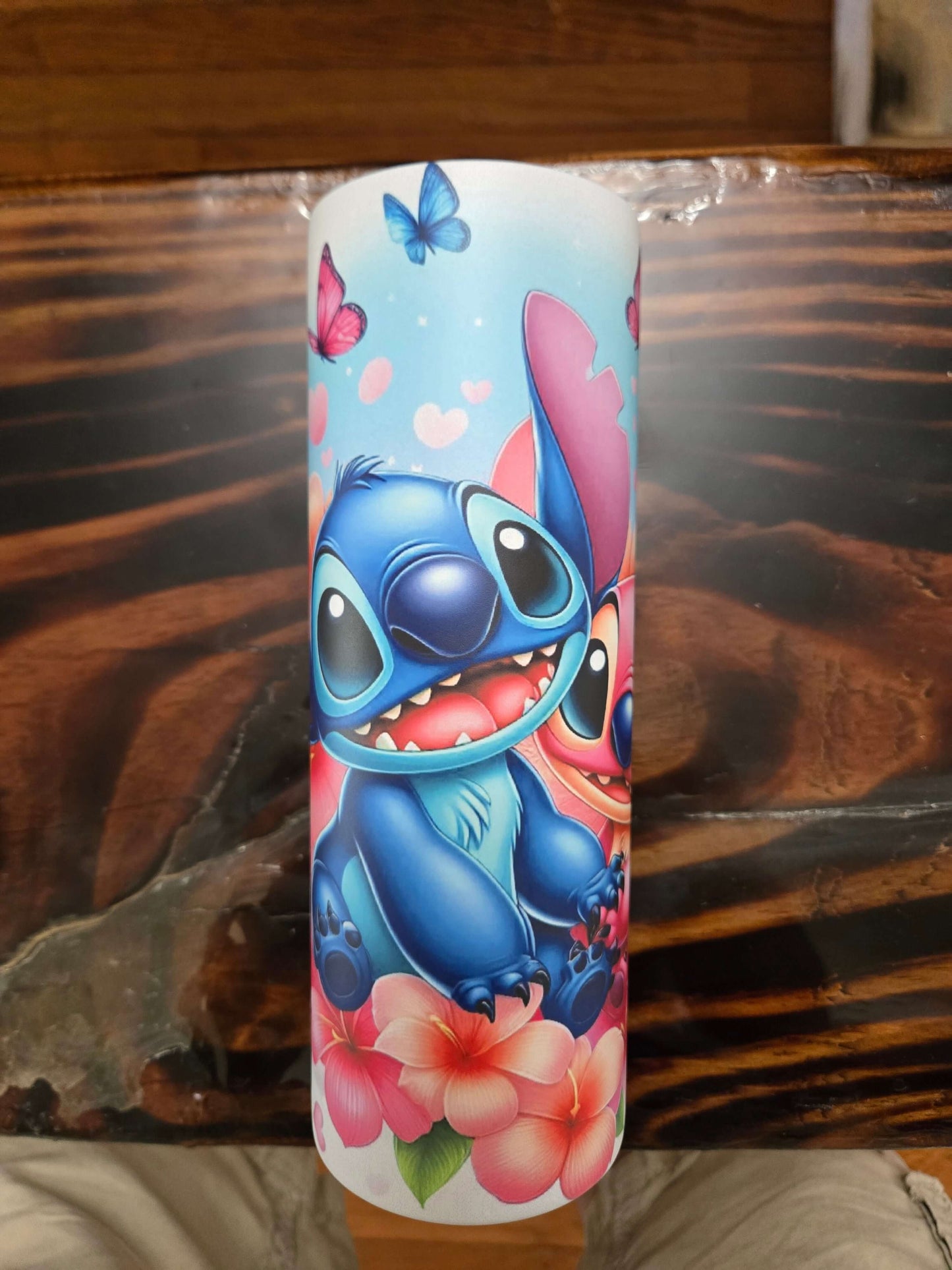 Colorful Stitch and Angel tumbler design featuring vibrant flowers and butterflies, perfect for Disney fans.