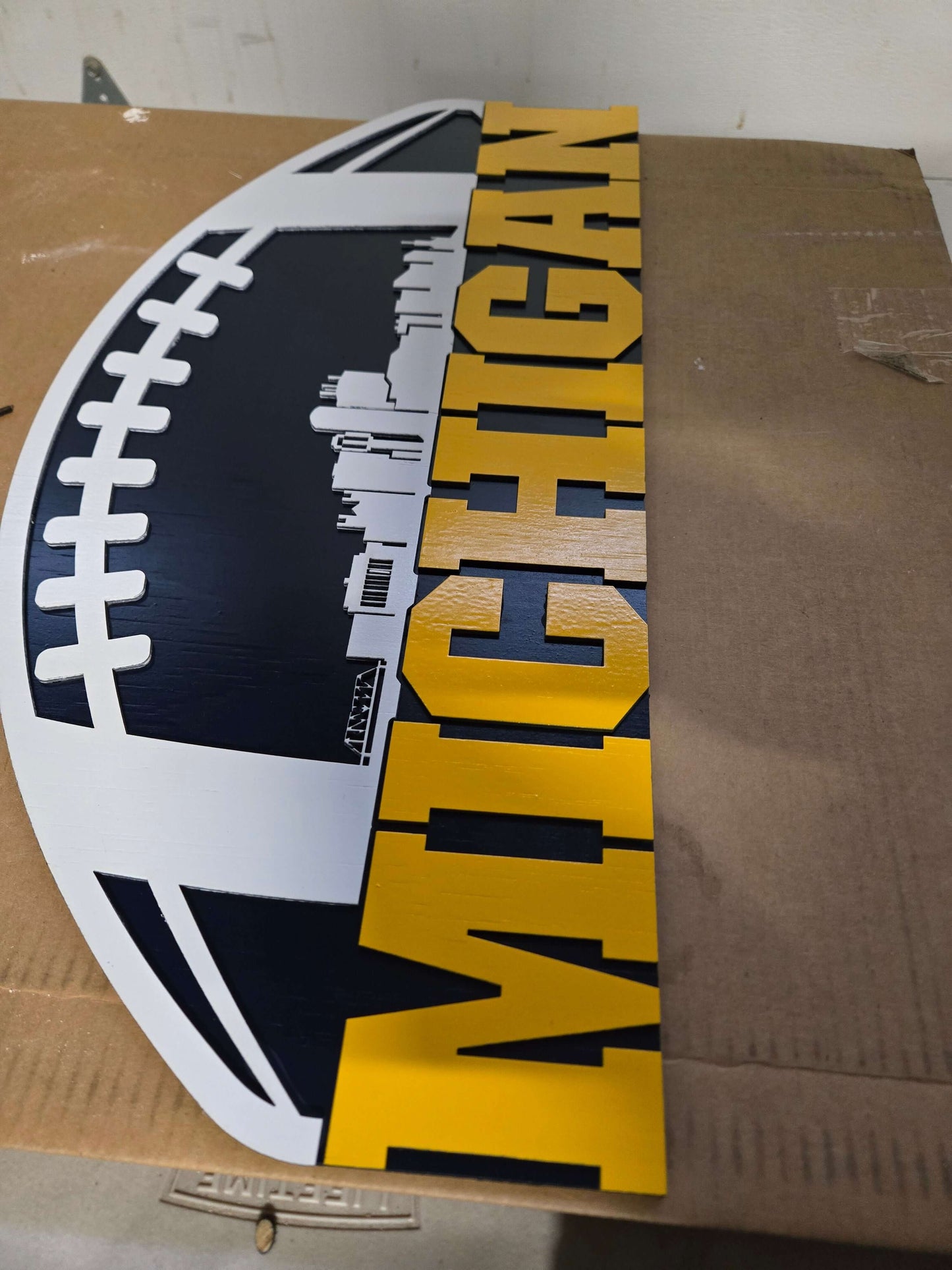 Michigan wooden decor sign featuring football design and city background.