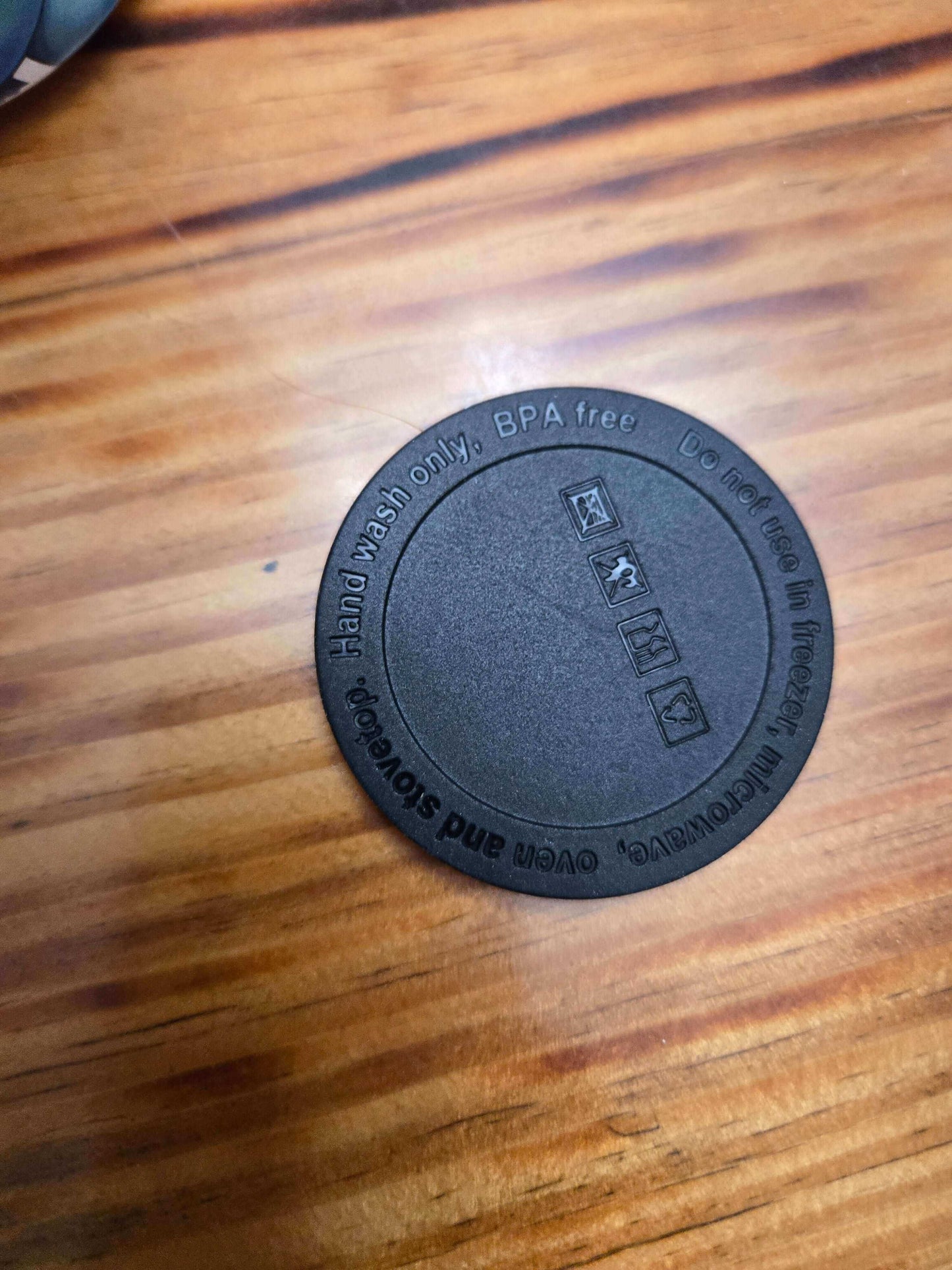 Bottom view of a black BPA-free tumbler lid, showcasing care instructions and recycling icons.