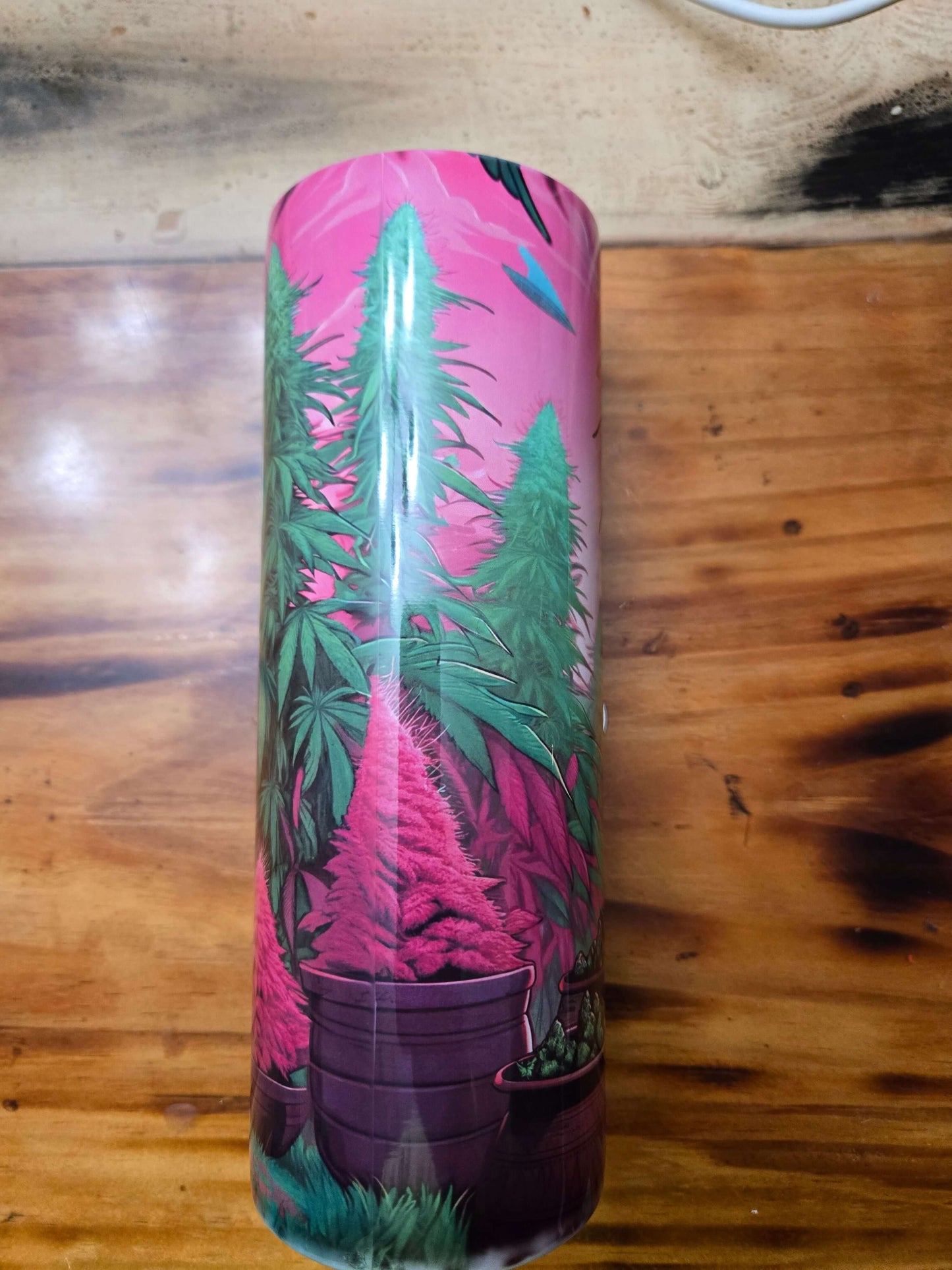 Vibrant 20oz tumbler showcasing alien hippie aesthetics with colorful cannabis plants against a pink background.