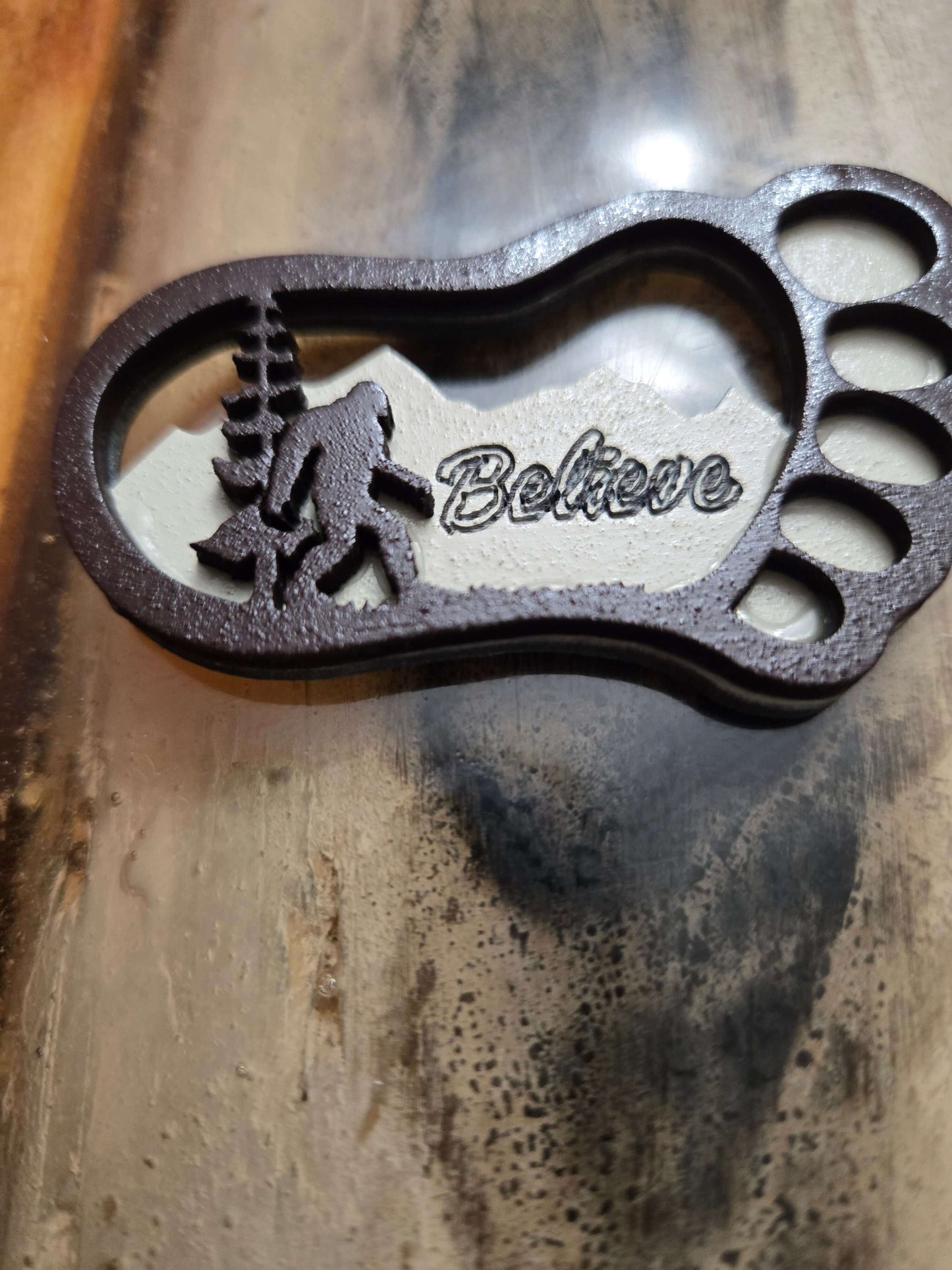 Bigfoot keychain with carved design and 'Believe' text, perfect for travel and outdoor enthusiasts.