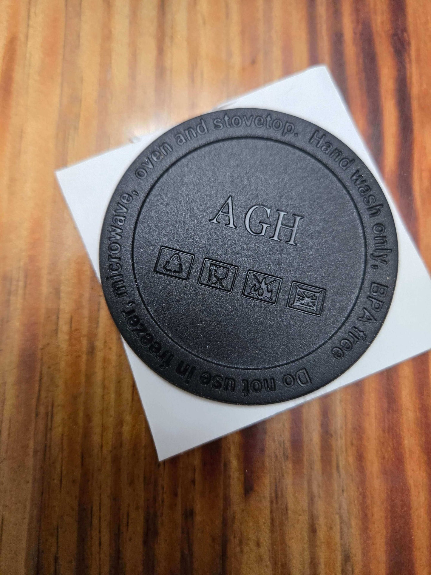 Round black lid with AGH branding and care instructions for microwave and stovetop use.