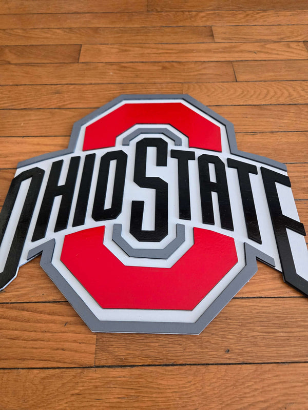 Ohio State logo sign featuring bold red and black colors on a wooden background.