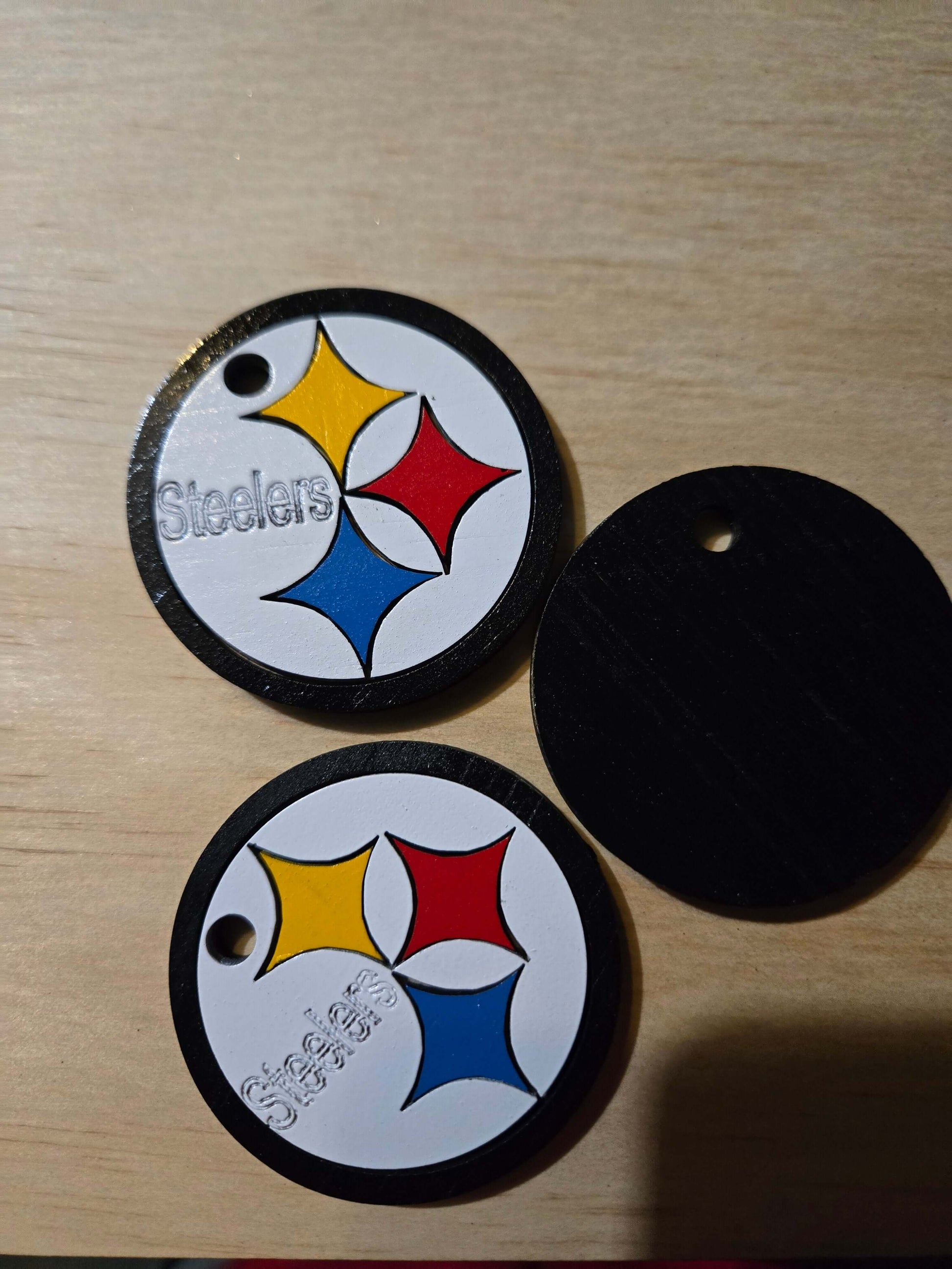 Steelers logo football keychains featuring vibrant colors on a wooden surface.