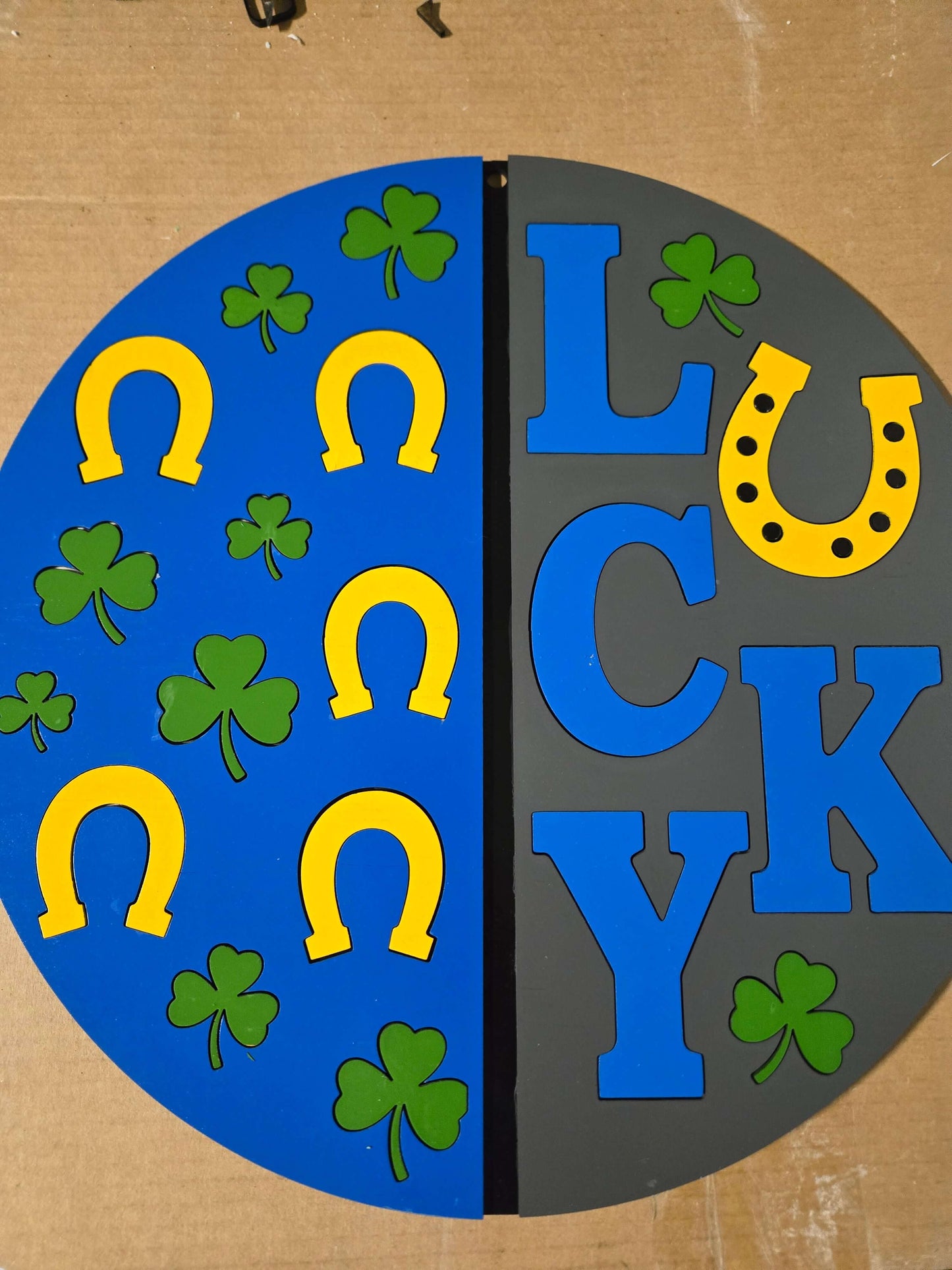 Lucky St. Patrick's Day wooden decor sign with yellow horseshoes and green clovers on a blue and gray background.