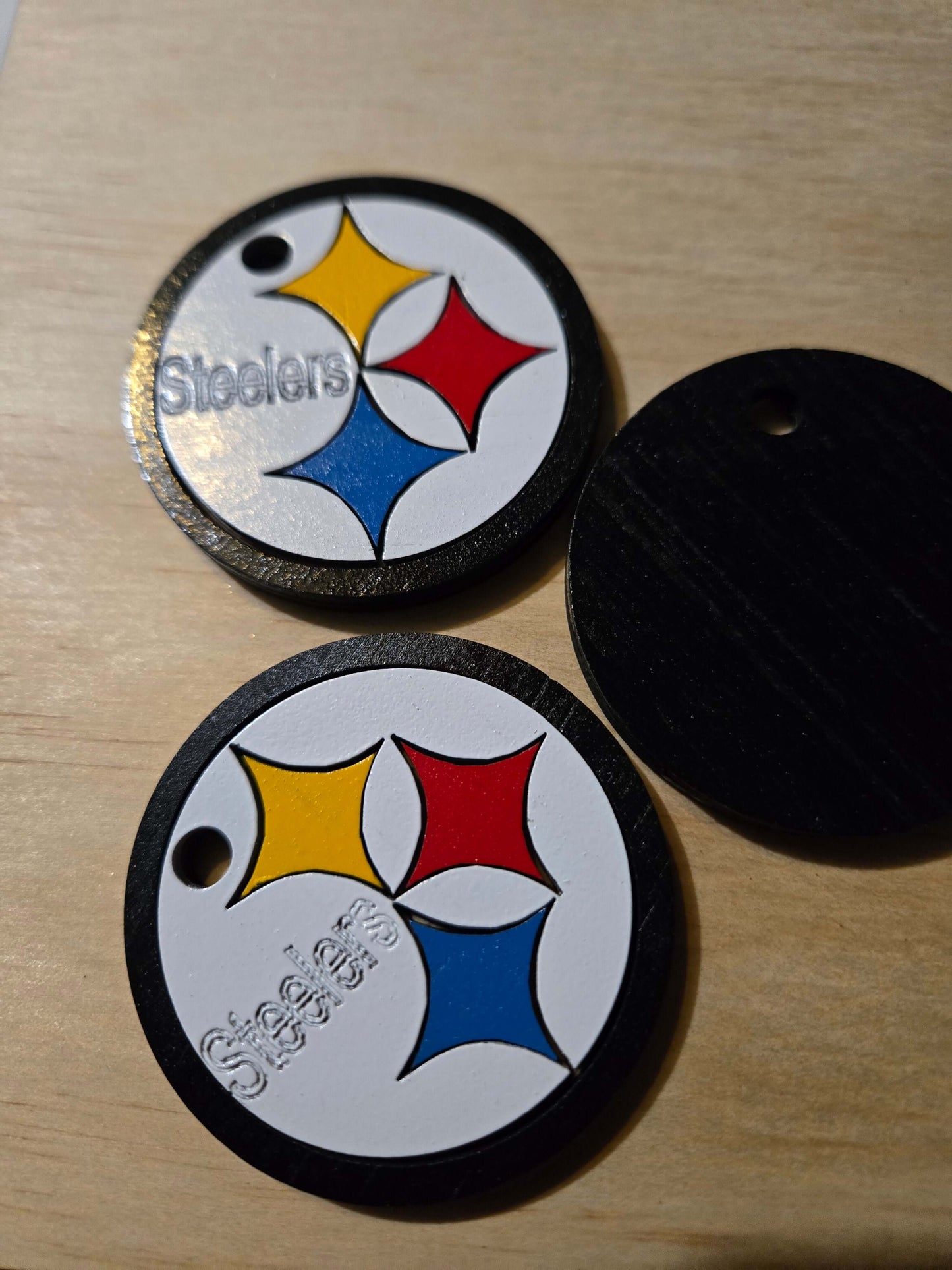 Pittsburgh Steelers logo keychains in vibrant colors on a wooden surface.