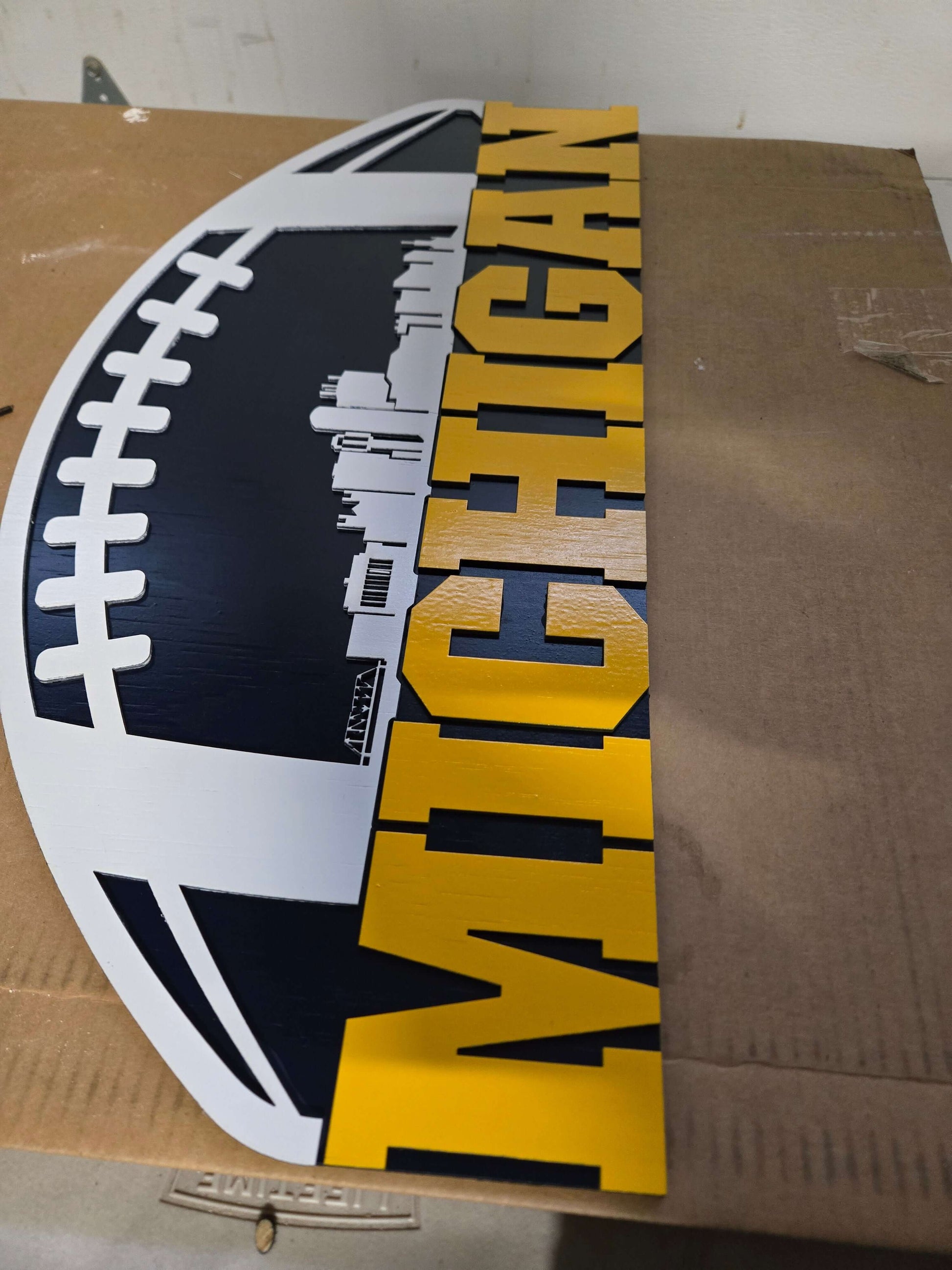 Michigan wooden decor sign featuring football design and city background.