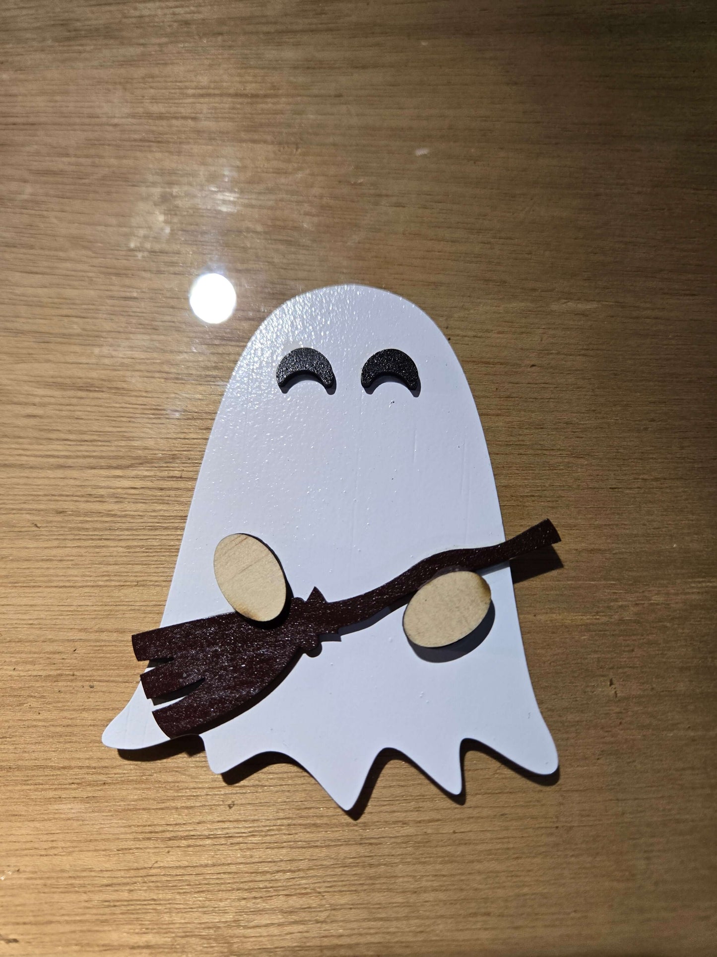 Small ghost holding a broom, perfect for holiday decor magnets, adds charm to any festive display.