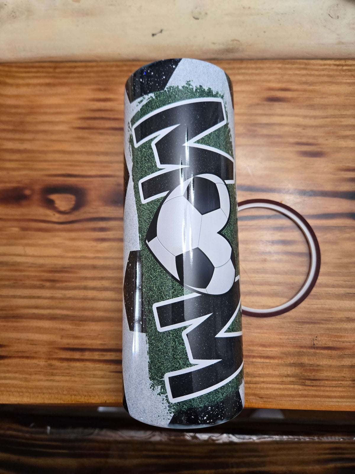 Soccer mom boss mom 20 oz tumbler cups with soccer design on a wooden surface.