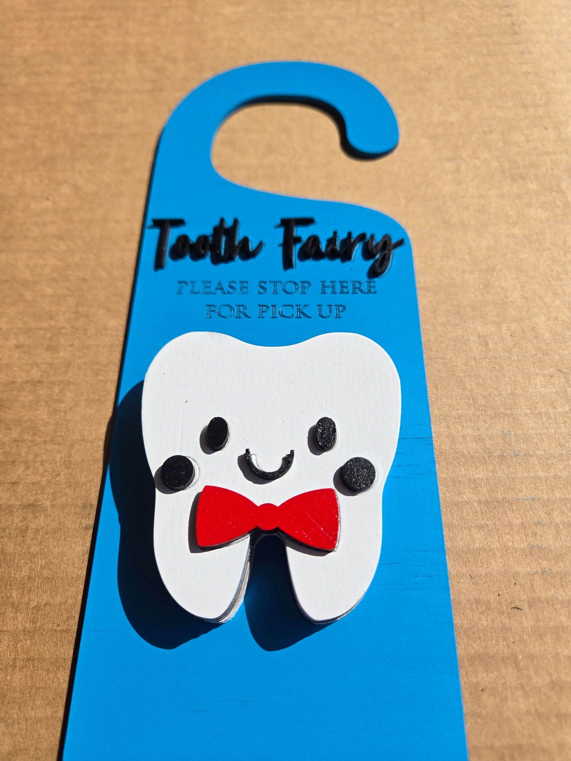 Tooth fairy door knob hanger featuring a smiling tooth with a red bow tie, perfect for kids' bedtime magic.
